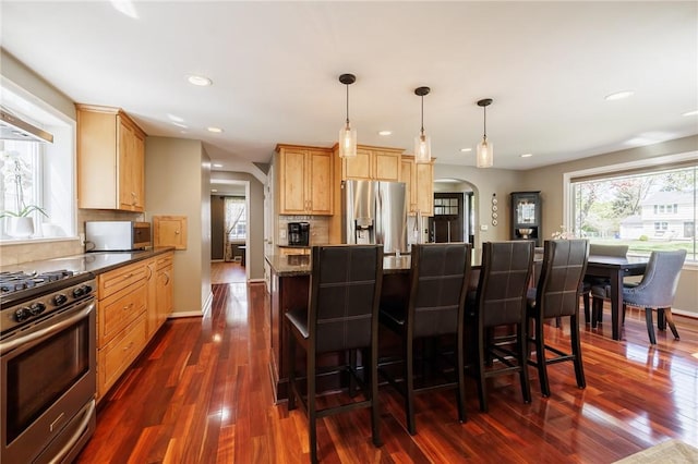 kitchen with stainless steel appliances, arched walkways, backsplash, dark wood-type flooring, and recessed lighting