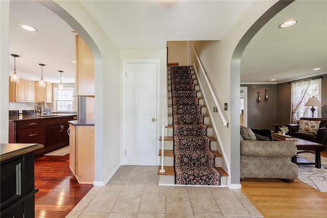 entrance foyer with arched walkways, stairs, recessed lighting, baseboards, and wood finished floors