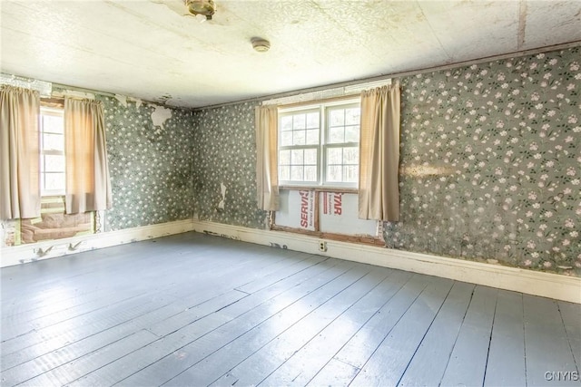 37931 State Route 12e, Clayton, NY 13624 - unfurnished room with wood-type flooring, healthy amount of natural light, baseboards, and wallpapered walls