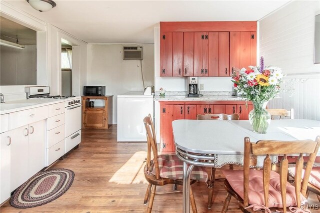 37931 State Route 12e, Clayton, NY 13624 - kitchen featuring white range with gas stovetop, black microwave, washer / dryer, light wood-style floors, and a wall unit AC