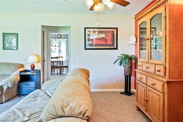 living area featuring light colored carpet, a ceiling fan, and baseboards