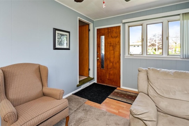 sitting room featuring baseboards, crown molding, a ceiling fan, and wood finished floors