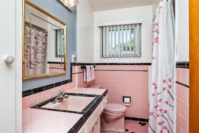 full bathroom featuring tile walls, tile patterned flooring, toilet, wainscoting, and vanity