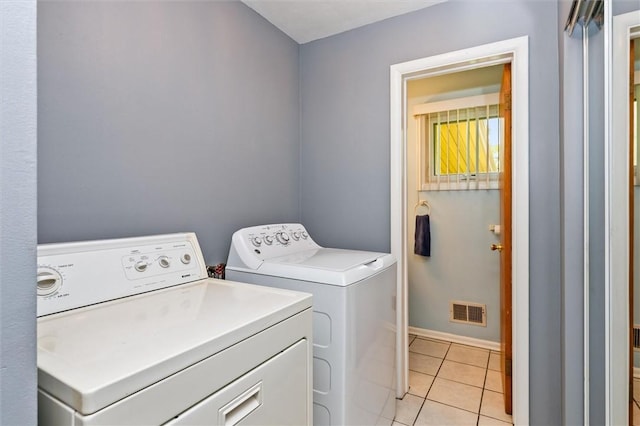 clothes washing area with separate washer and dryer, light tile patterned floors, and baseboards