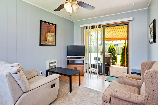 carpeted living room with crown molding, heating unit, and ceiling fan