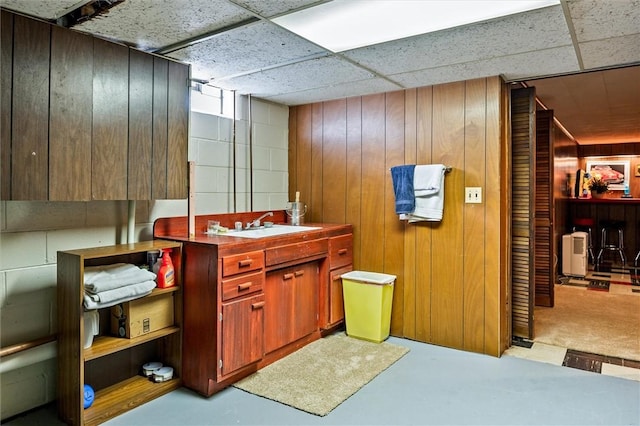 bathroom featuring wood walls, a sink, and concrete floors
