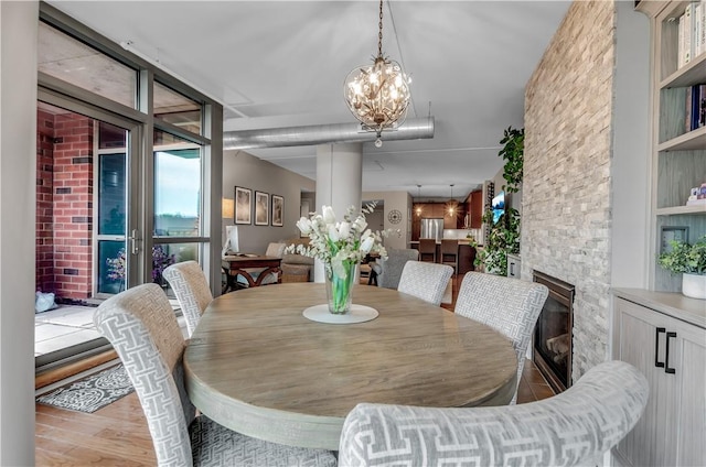 132 Lakefront Blvd Unit 104, Buffalo, NY 14202 - dining room with wood finished floors, a chandelier, and a stone fireplace