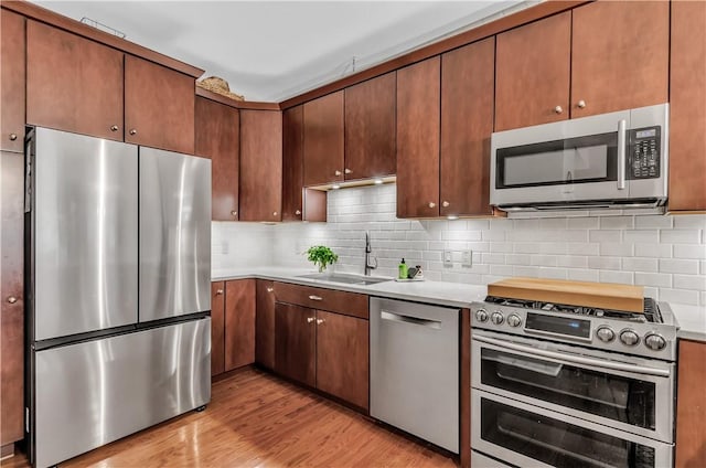 132 Lakefront Blvd Unit 104, Buffalo, NY 14202 - kitchen featuring stainless steel appliances, a sink, light wood-type flooring, light countertops, and backsplash