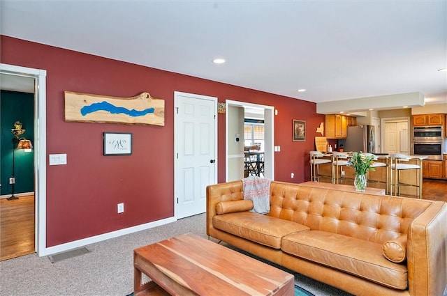 living room featuring recessed lighting, baseboards, and light carpet