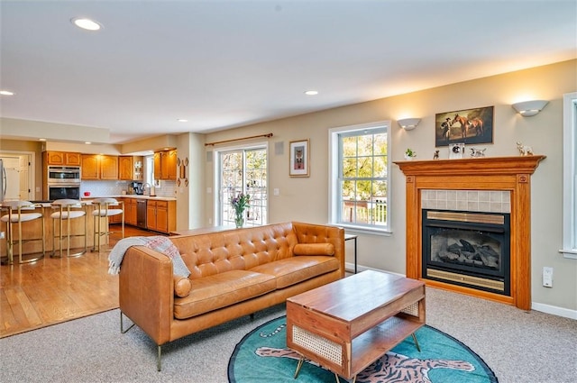 living room with recessed lighting, light colored carpet, a tile fireplace, and baseboards