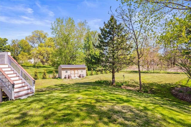 view of green lawn with an outdoor structure, stairway, a storage unit, and view of wooded area