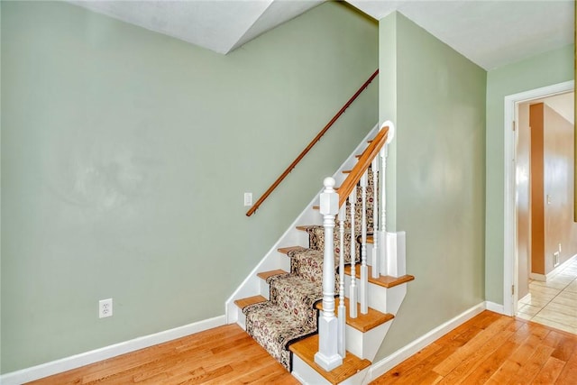 staircase featuring wood finished floors and baseboards