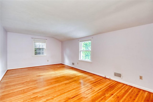 unfurnished room with lofted ceiling, plenty of natural light, wood finished floors, and baseboards