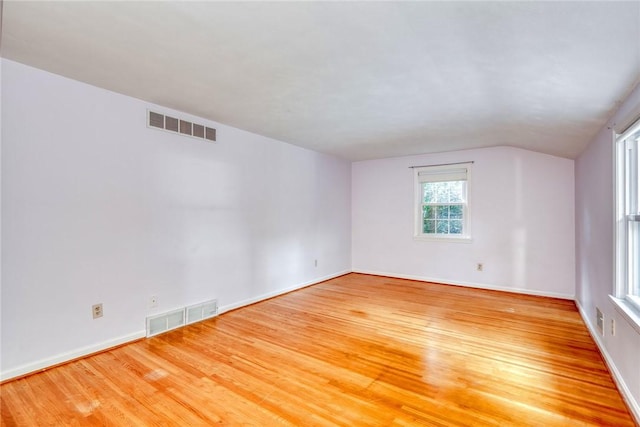 unfurnished room with wood finished floors, baseboards, and lofted ceiling