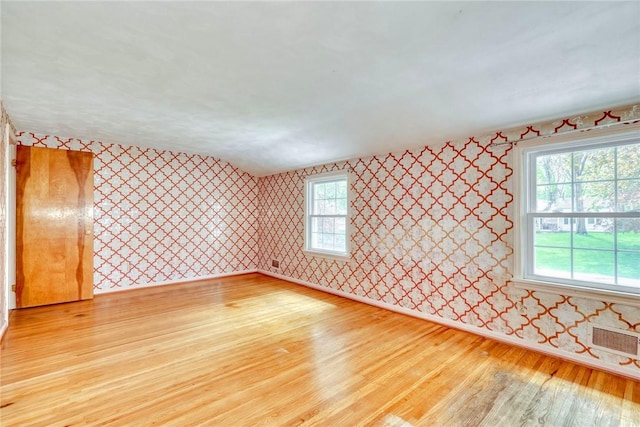 unfurnished room featuring wallpapered walls, light wood-style floors, and baseboards