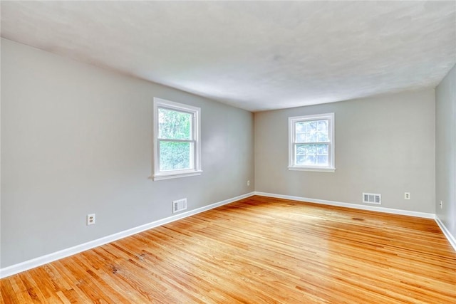 spare room featuring plenty of natural light, baseboards, and light wood-style flooring