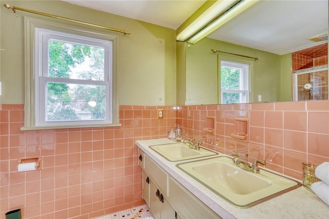 full bath with tile walls, tiled shower, a wainscoted wall, and double vanity