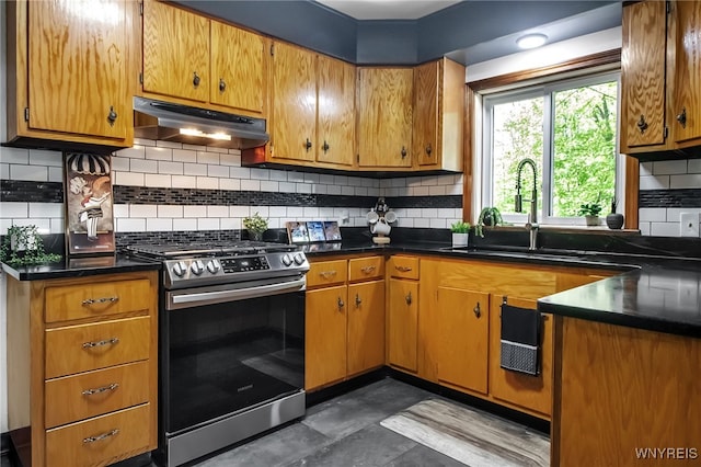 kitchen with stainless steel gas range, under cabinet range hood, a sink, dark countertops, and tasteful backsplash