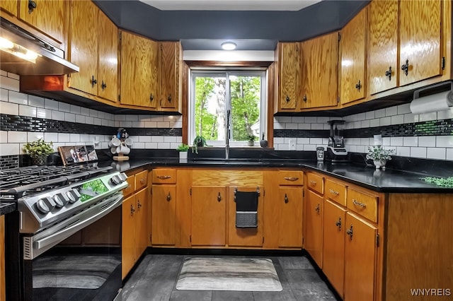 kitchen with gas range, under cabinet range hood, a sink, and brown cabinets