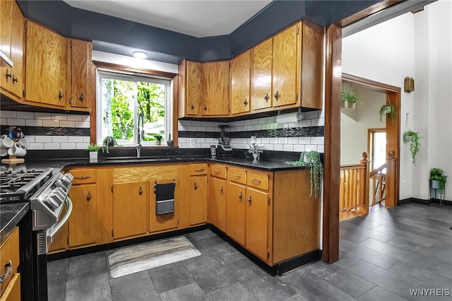 kitchen featuring gas range, dark countertops, decorative backsplash, a sink, and brown cabinets