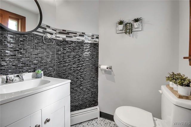 half bath featuring baseboard heating, toilet, tile walls, and vanity