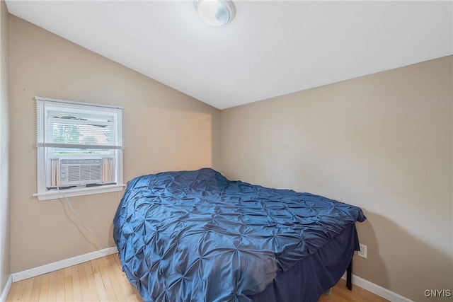 bedroom featuring vaulted ceiling, cooling unit, baseboards, and wood finished floors