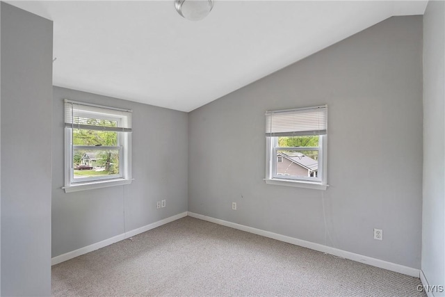 carpeted spare room featuring vaulted ceiling, healthy amount of natural light, and baseboards