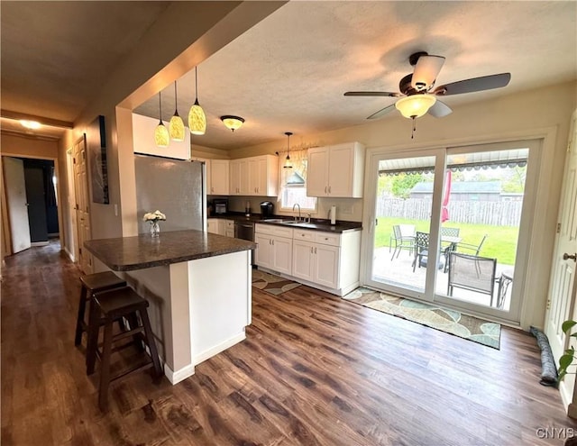 1004 W Thomas St, Rome-Inside, NY 13440 - kitchen with freestanding refrigerator, dark countertops, white cabinets, dishwashing machine, and dark wood-style floors