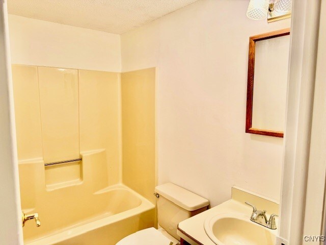 345 Orton Rd, Sandy Creek, NY 13142 - bathroom with toilet, vanity, a textured ceiling, and washtub / shower combination