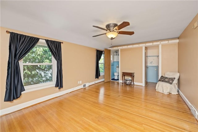 unfurnished room featuring light wood-type flooring, a ceiling fan, and baseboards