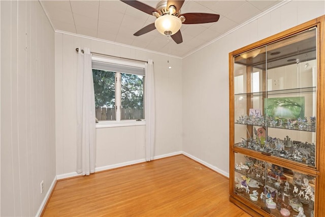 unfurnished room with ornamental molding, light wood-type flooring, ceiling fan, and baseboards