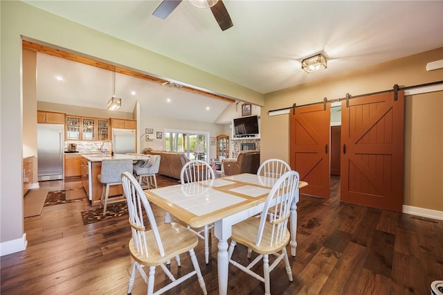 dining area with a barn door, ceiling fan, dark wood finished floors, and baseboards