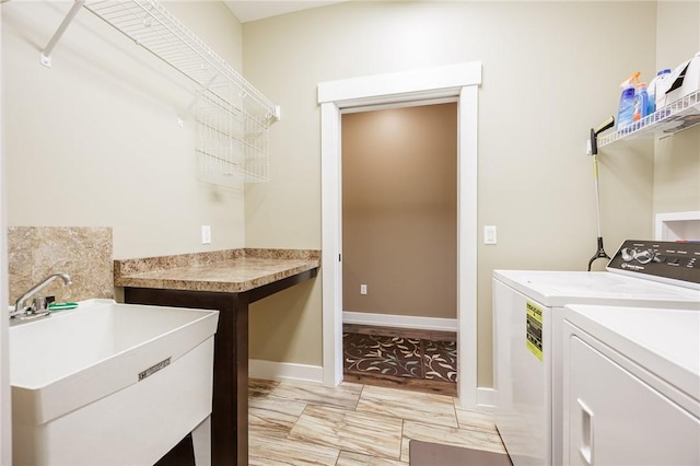 washroom featuring washing machine and clothes dryer, light marble finish flooring, and baseboards
