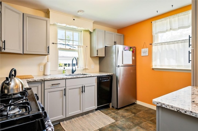 kitchen with a sink, black appliances, baseboards, gray cabinets, and light stone countertops