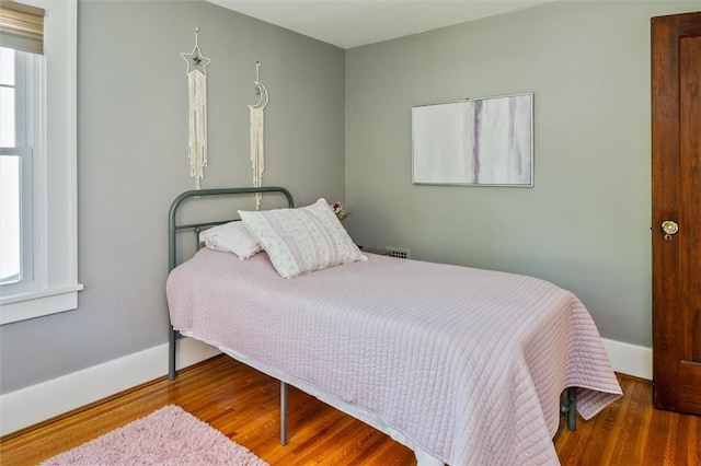 bedroom with wood finished floors, multiple windows, and baseboards