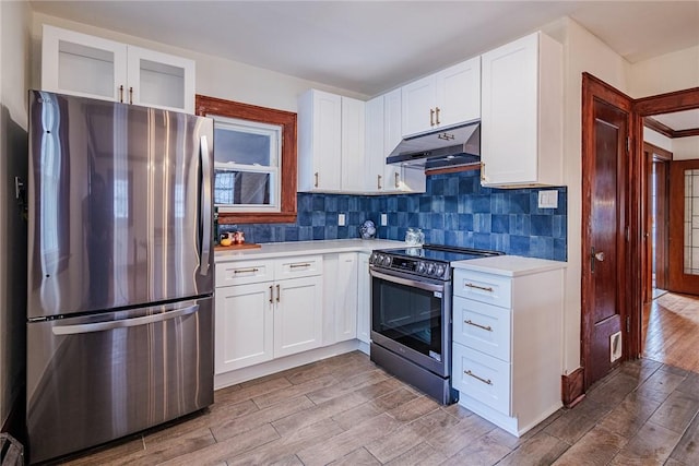 kitchen with stainless steel appliances, under cabinet range hood, wood finished floors, light countertops, and white cabinetry