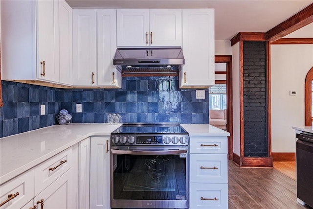 kitchen featuring electric stove, under cabinet range hood, wood finished floors, backsplash, and light countertops