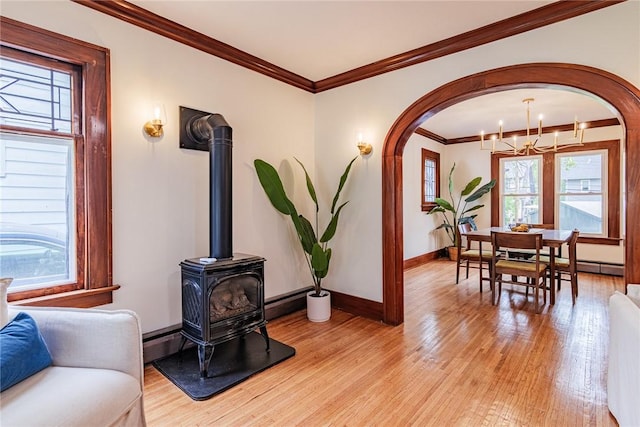 living area featuring healthy amount of natural light, light wood-style floors, a wood stove, and crown molding