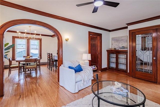 living area featuring arched walkways, ornamental molding, light wood-style flooring, and baseboards
