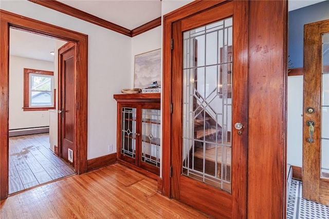 doorway with a baseboard radiator, wood finished floors, crown molding, and baseboards