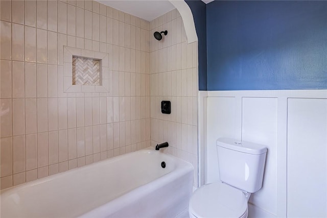bathroom with shower / bath combination, toilet, and wainscoting