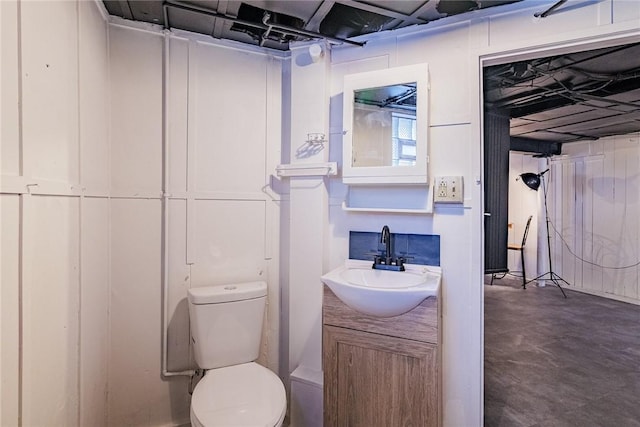 bathroom featuring concrete floors, toilet, and vanity