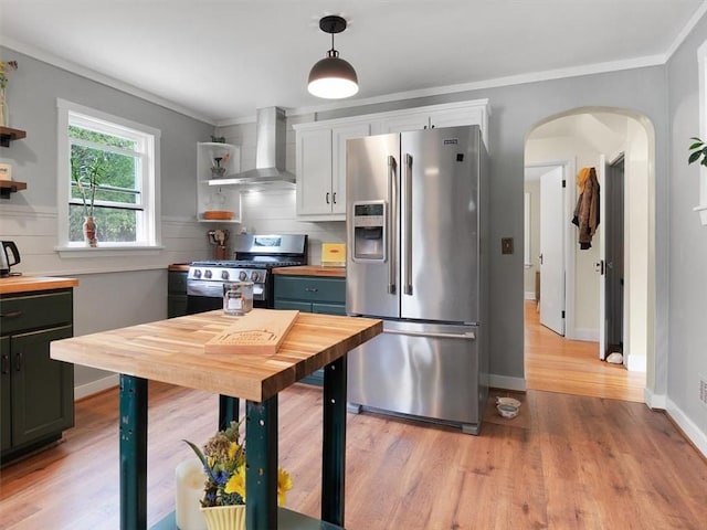 kitchen with appliances with stainless steel finishes, wall chimney exhaust hood, open shelves, wooden counters, and crown molding