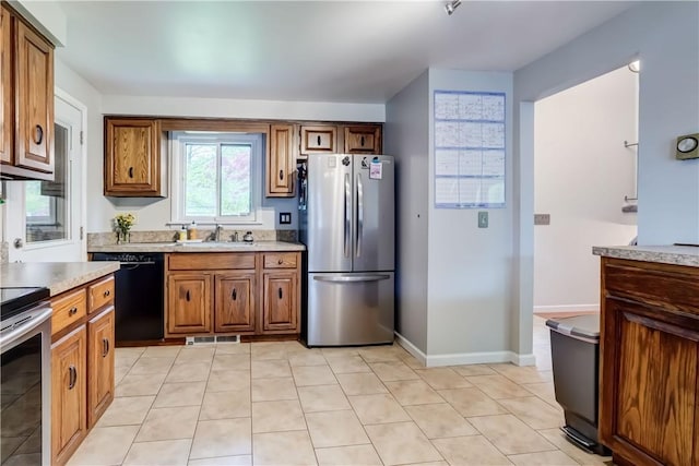 kitchen featuring appliances with stainless steel finishes, brown cabinetry, light countertops, and a sink