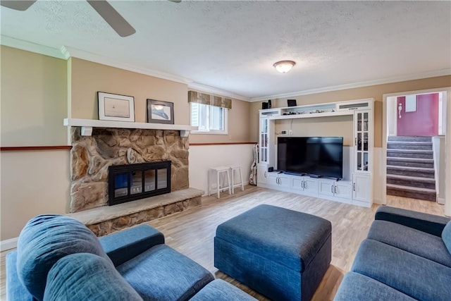 living room featuring crown molding, wood finished floors, a ceiling fan, a textured ceiling, and stairs