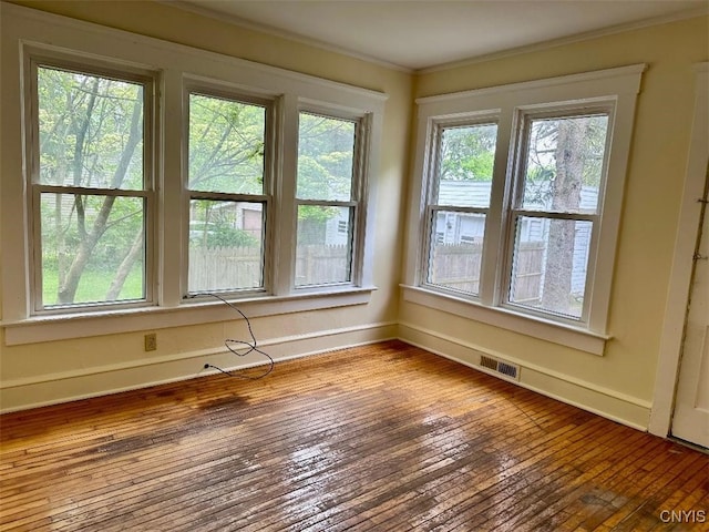 empty room with ornamental molding, baseboards, and hardwood / wood-style flooring