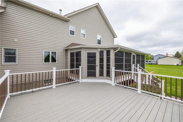 wooden terrace featuring a sunroom and a lawn