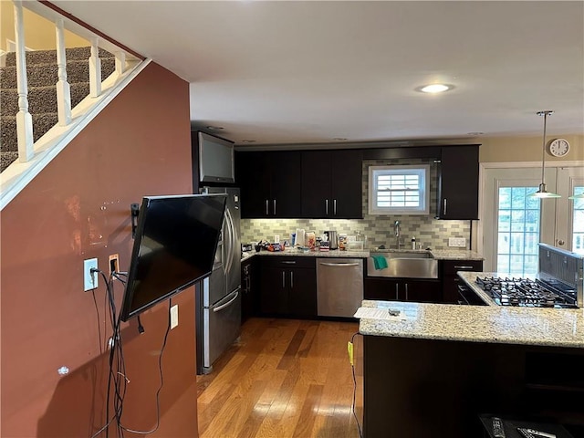 407 Gifford St, Hornellsville, NY 14843 - kitchen featuring a sink, appliances with stainless steel finishes, dark cabinetry, light wood-type flooring, and tasteful backsplash