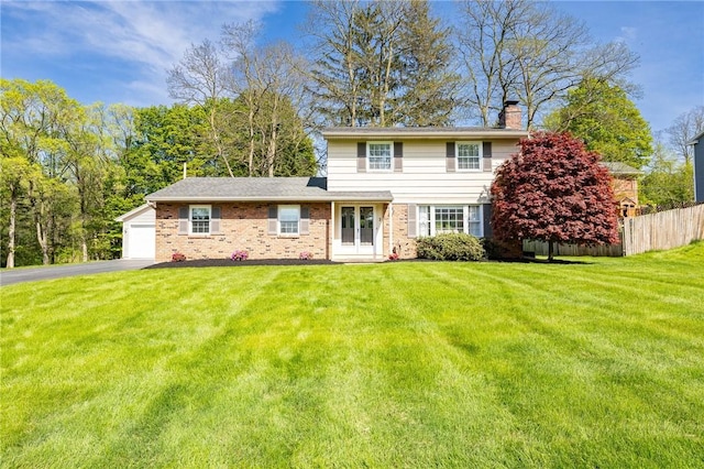 traditional-style house featuring a chimney, driveway, brick siding, french doors, and an attached garage