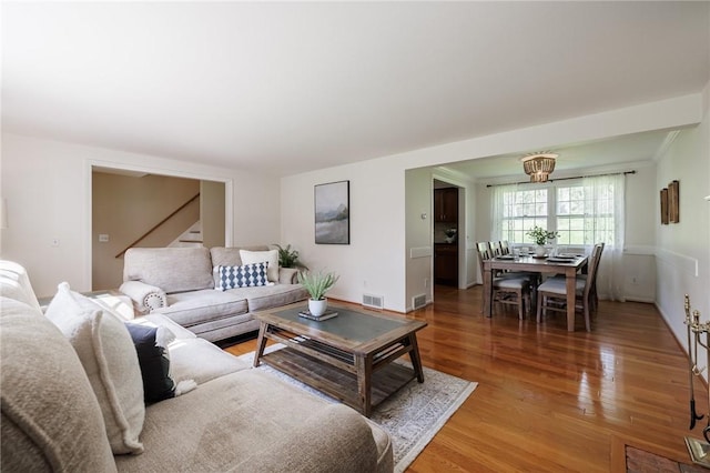 living area featuring light wood-style flooring, stairs, and baseboards